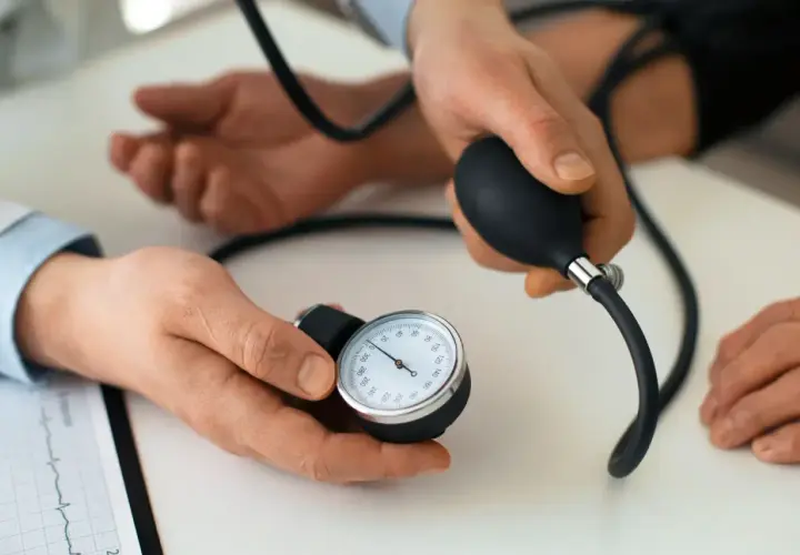 Lekarz mierzy ciśnienie pacjentowi za pomocą ciśnieniomierza. Karbis jest kluczowy w diagnostyce.