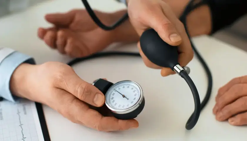 Lekarz mierzy ciśnienie pacjentowi za pomocą ciśnieniomierza. Karbis jest kluczowy w diagnostyce.