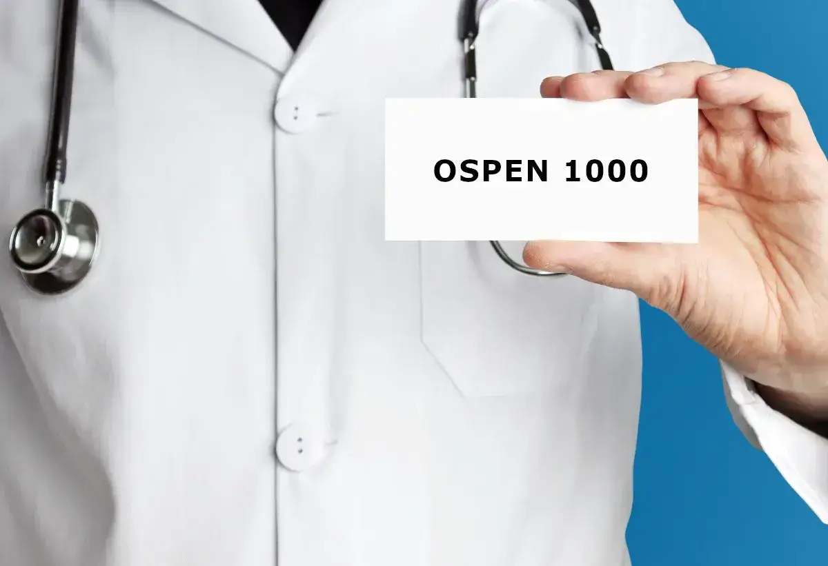 Lekarz w białym kitlu trzyma kartkę z napisem OSPEN 1000. Stetoskop wisi na szyi.