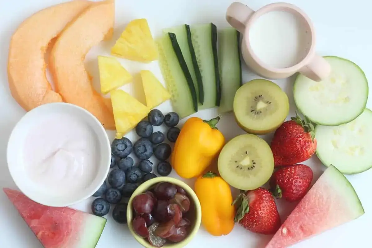Kolorowe owoce i warzywa: melon, ananas, borówki, kiwi, truskawki, winogrona, papryka, ogórek i jogurt. Idealne na lekki posiłek, by uniknąć biegunki.